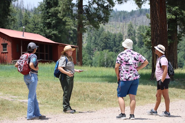 A park ranger addresses 3 visitors during a walk through the Cabin District.