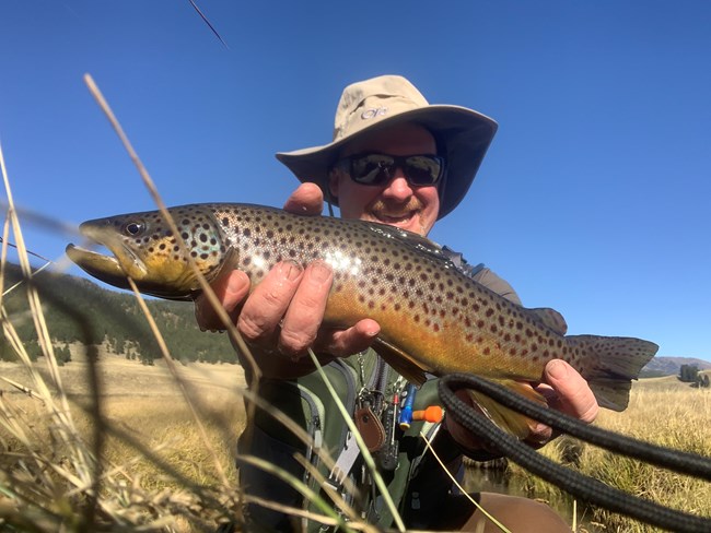 An angler holds up a large trout