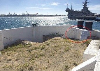 A view inside on of the mooring quays showing damage to the concrete. The USS Missouri Battleship is in the background.