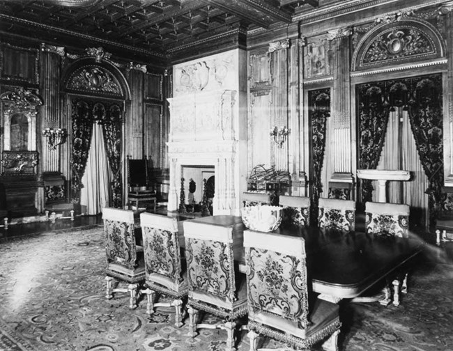 A black and white photograph of a grand dining room.