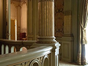 A column inside a room and door beyond with furnishings.