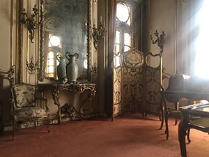 A room with gilt walls and raking light through a window.