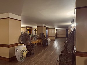 An oval shaped room with large table, flowers, trunks, and stored furntiture.