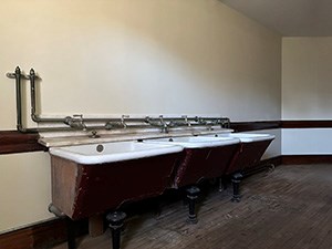 A room with three washtubs mounted to the wall.