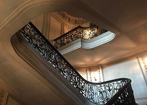 A stone staircase with decorative bronze railing rising three flights.