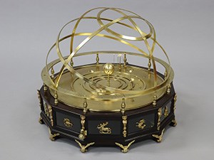 A twelve-sided wooden case supporting a brass model of the solar system.