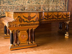 A grand piano decorated with floral garlands and portraits of composers