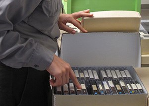 A pair of hands opening a box containing cassette tapes.