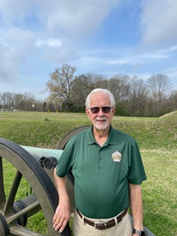 A man with white hair and green polo shirt.