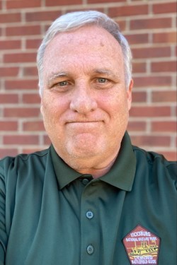 A man with white hair and green polo shirt.
