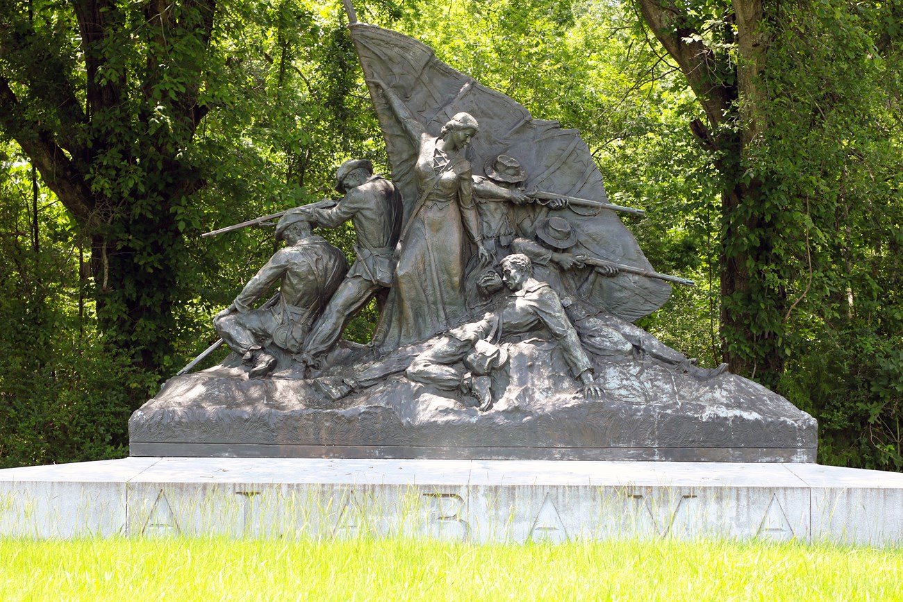 A bronze statue depicts soldiers surround a woman who holds up a flag