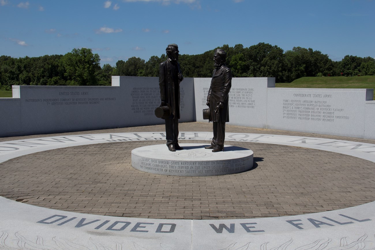Two statues stand in the middle of a circular design with words surrounding them.
