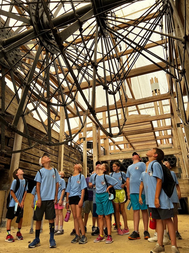 A group of kids standing under the paddlewheel of the USS Cairo.