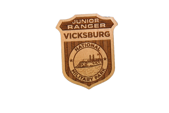 Jr Ranger Badge A wooden badge with an image of the USS Cairo in the middle. The badge reads Junior Ranger Vicksburg National Military Park