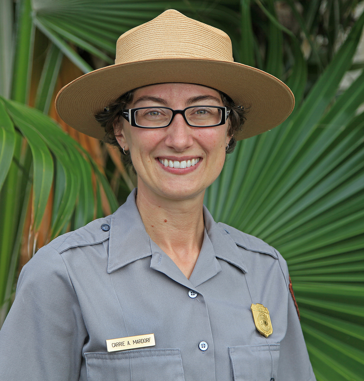 Carrie Mardorf Smiling women wearing a straw broad brimmed park ranger hat and a gray uniform shirt hat