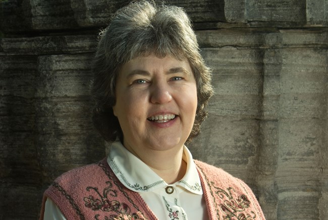 A woman with gray hair in a pint sweater.