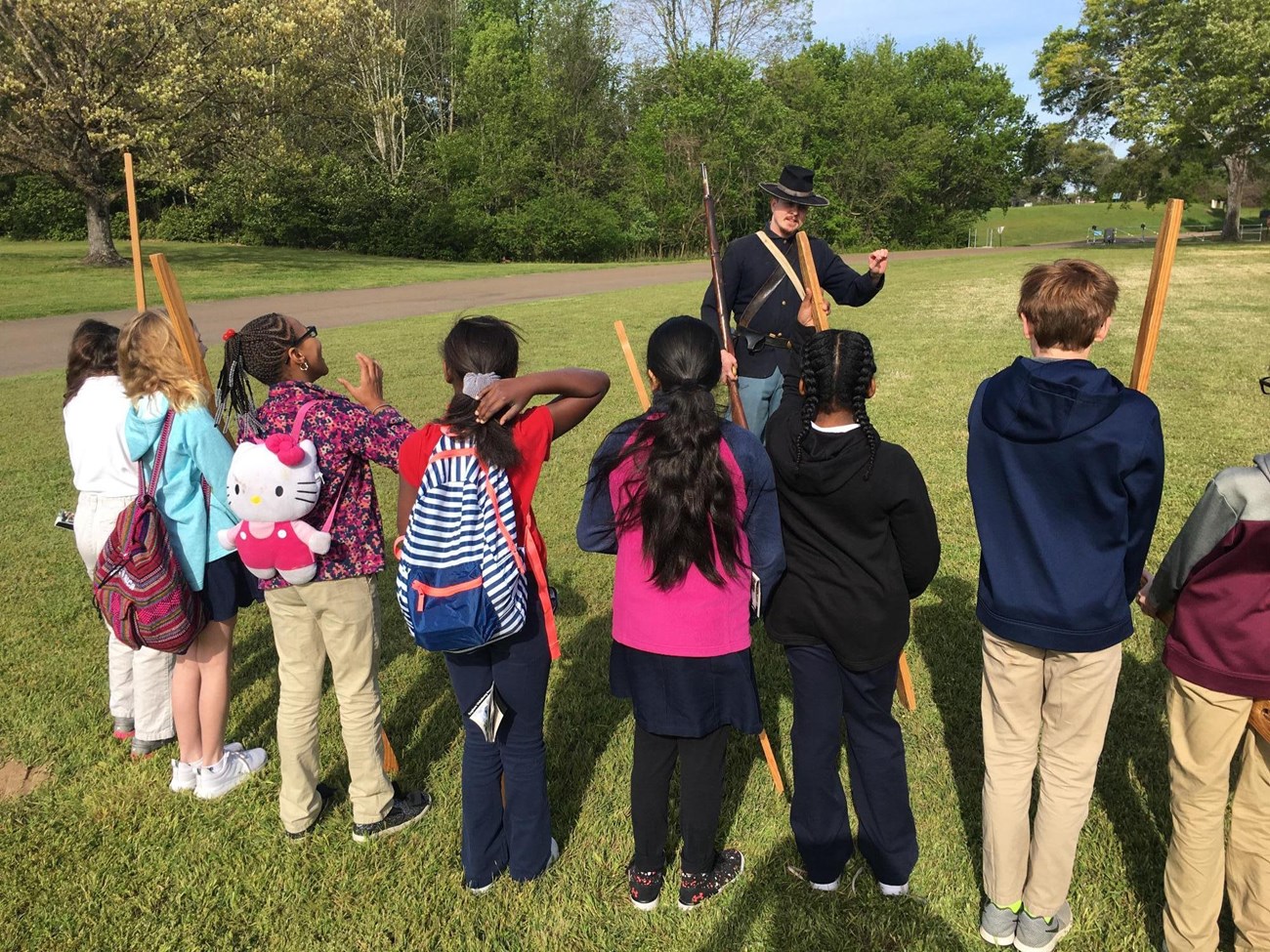 A park ranger dressed as a Union soldier talks to children holding wooden muskets.