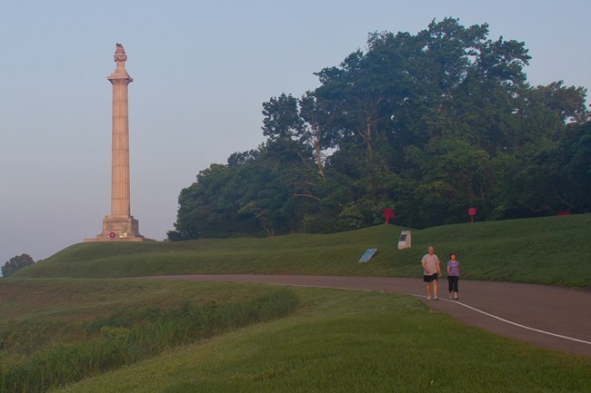 Two visitors walk along the paved tour road.