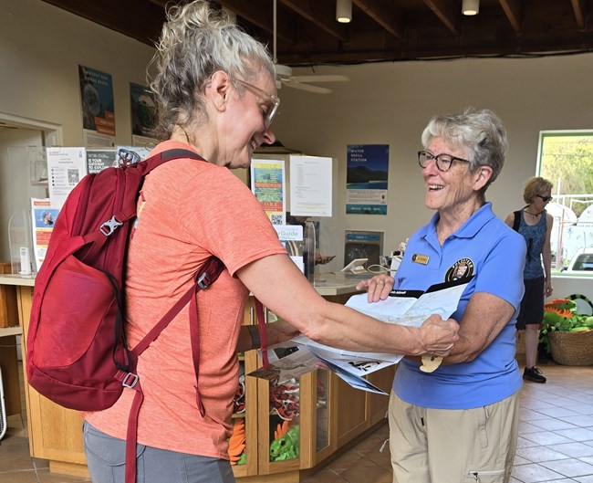 Two women in the visitor center smiling and looking at a map.