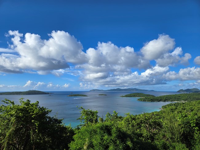 Image of Caneel Bay with blue water, white sand beach and green hills and islands.