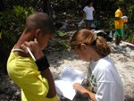 Two students are writing data on a clipboard on a field trip.