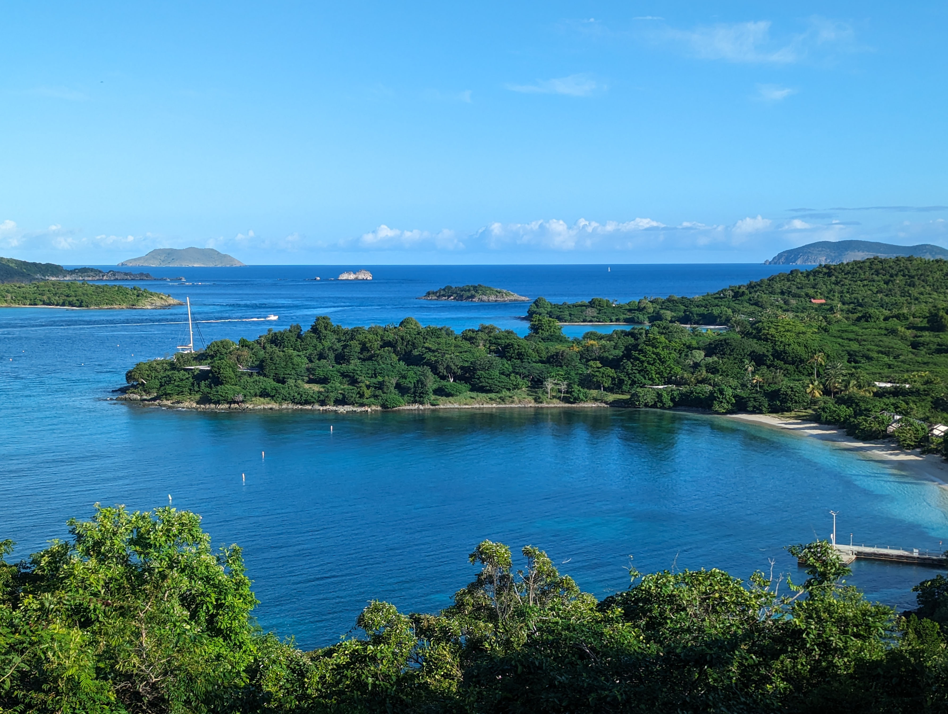 Overlook to Caneel Bay Image of Caneel Bay from the overlook with blue water and sky and white sand beaches with green hills and islands.