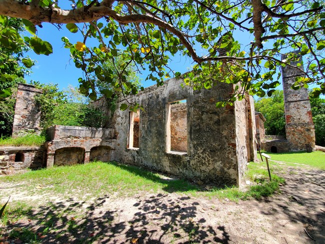 Reef Bay Sugar Factory, constructed from red brick, grey and brown fieldstone, and harvested coral heads, stands in contrast to the wooded landscape that surrounds it.