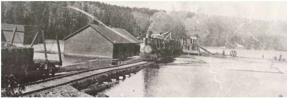 A historic photo of a railroad trestle and hoist built across the water to transport logs.