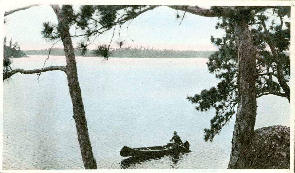 Historical photo of a person canoeing on a lake Historical photo of a person canoeing on a lake