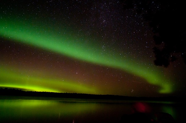 A multitude of colors light up the night sky, slight reflection of colors off the lake surface can be seen.