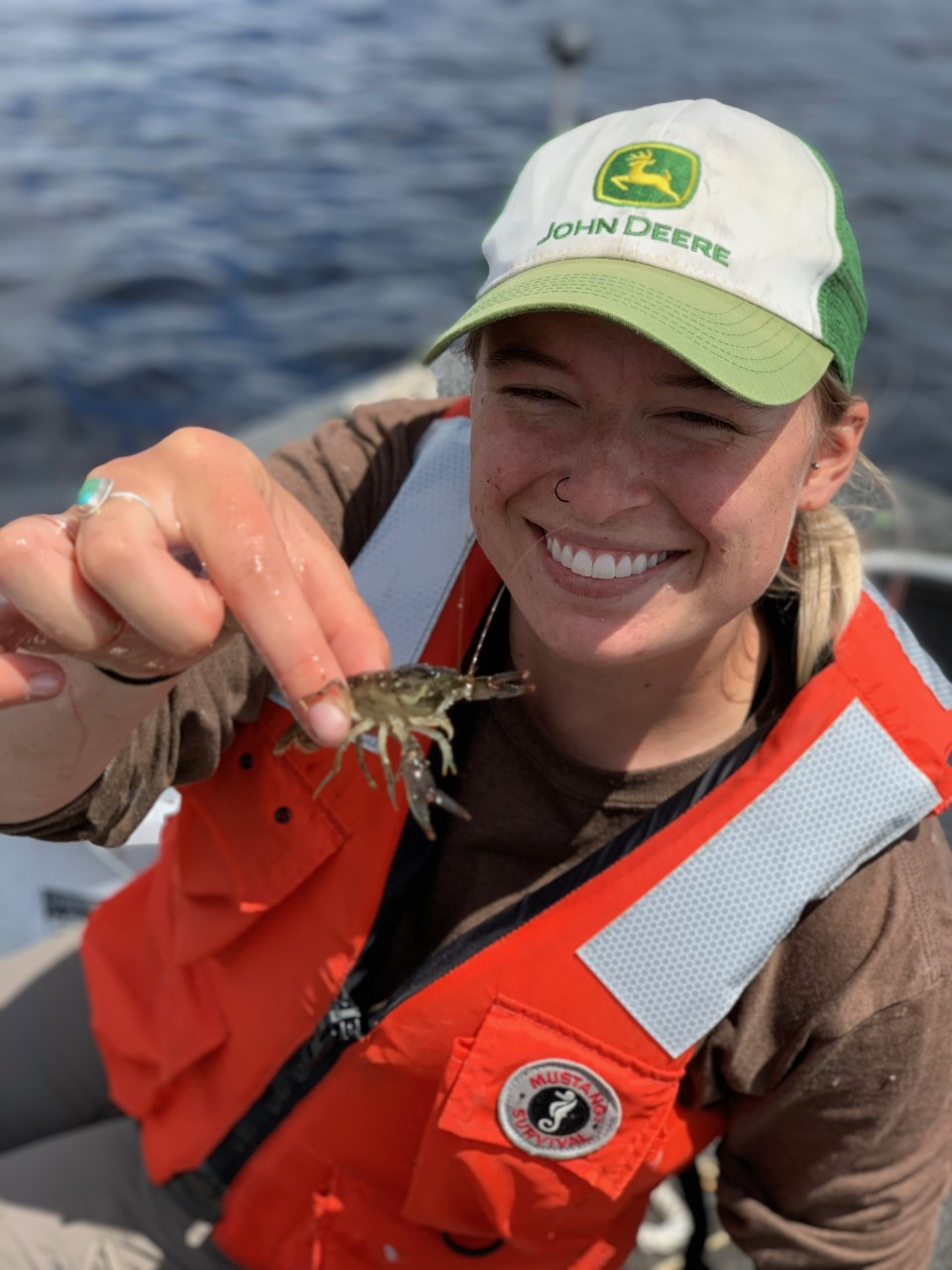 Ranger Cat holding a crayfish while sitting in a boat on a summer day.