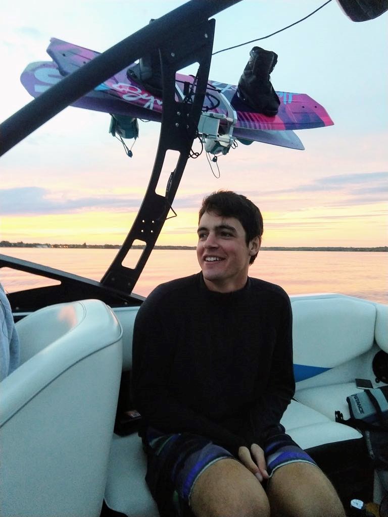 James Smith in a wakeboarding boat on a lake, on a summer day.