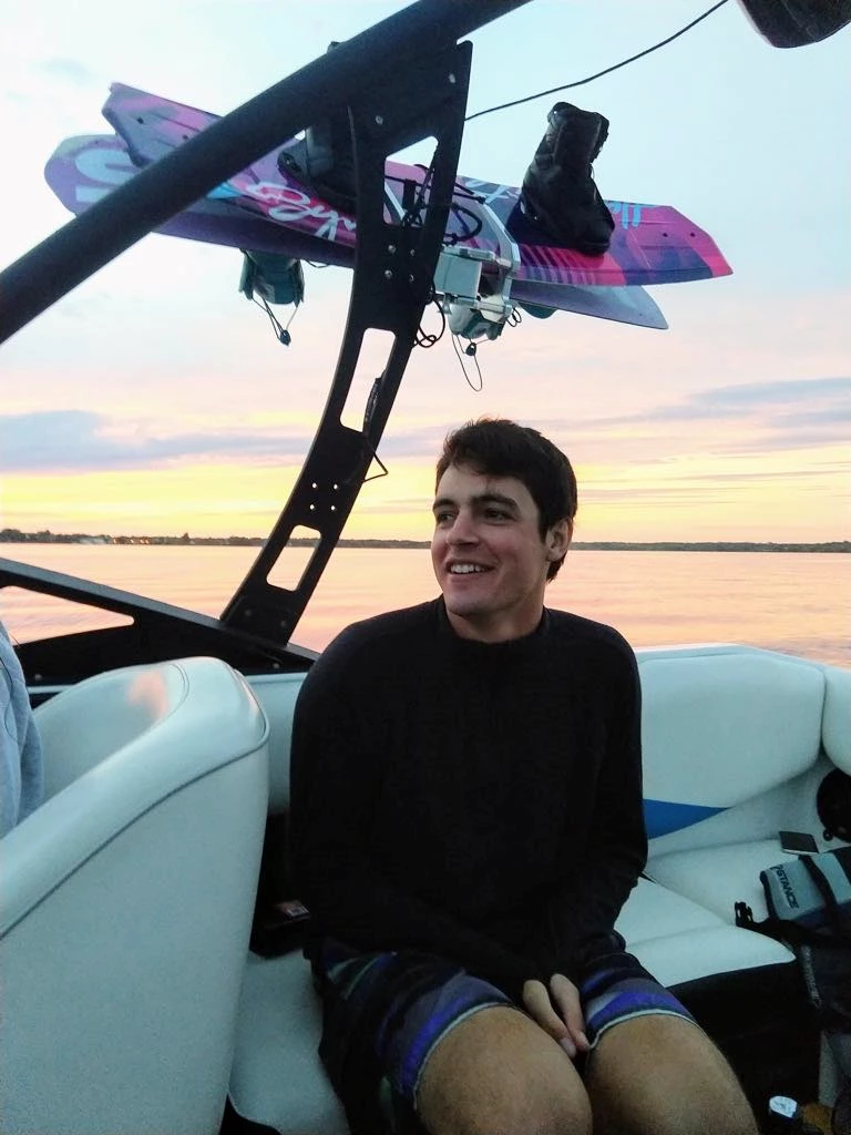 James Smith James Smith in a wakeboarding boat on a lake, on a summer day.