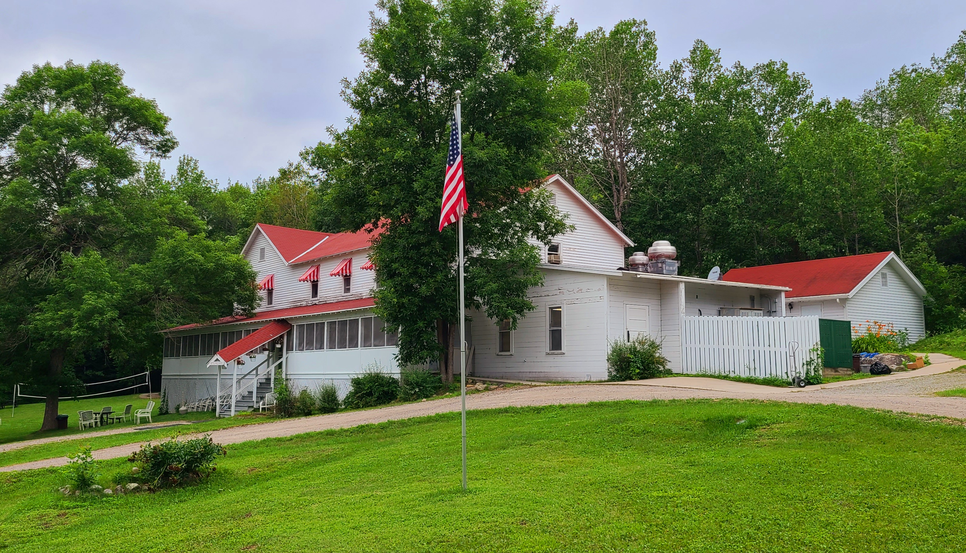 Historic red and white Kettle Falls Hotel with American flag and surrounding grounds.