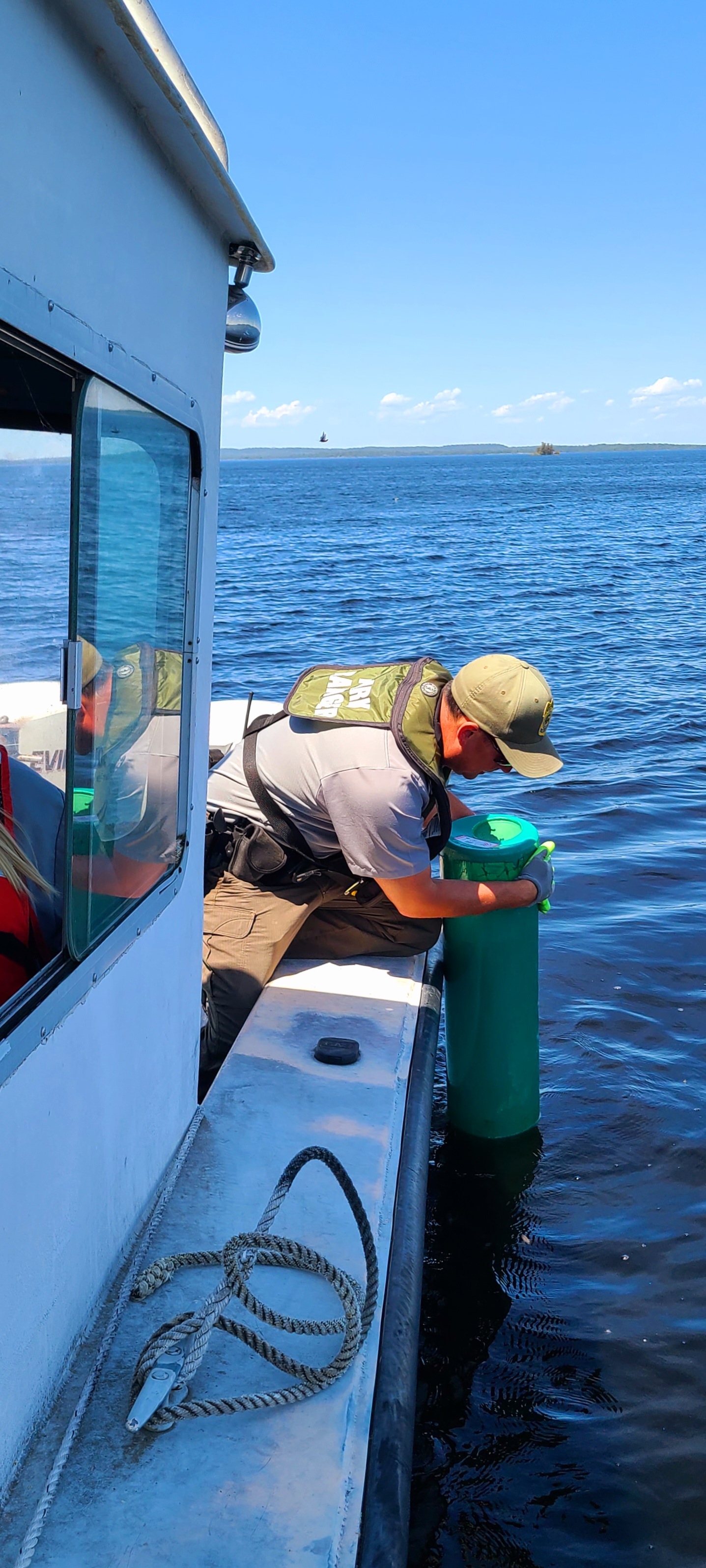 Park Ranger removing a buoy A Park Ranger reaches over the side of a boat to remove a buoy from Rainy Lake