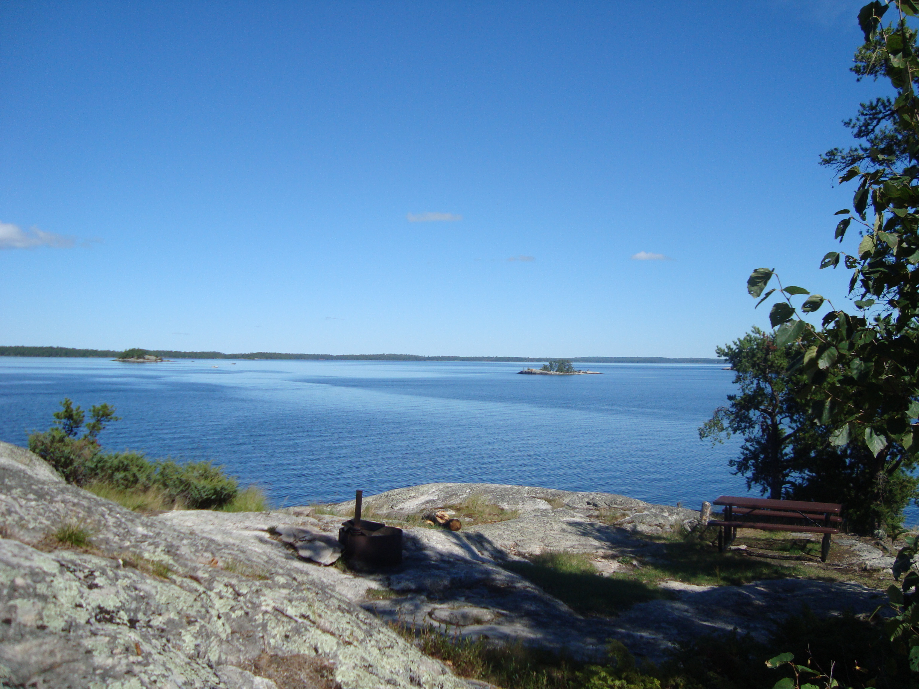 Campsite firepit with lake view in background.