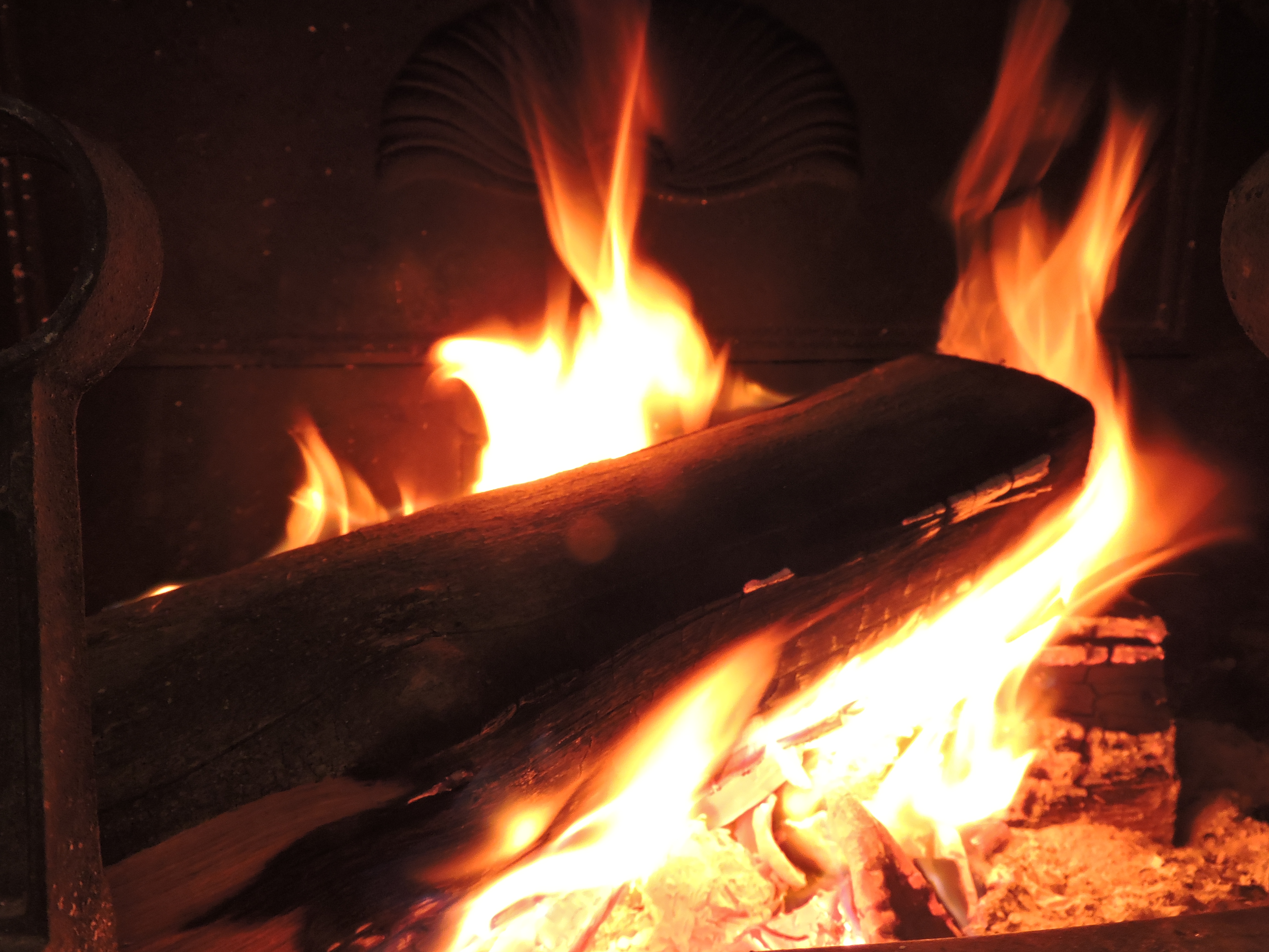 Burning firewood and orange glow from a campfire.
