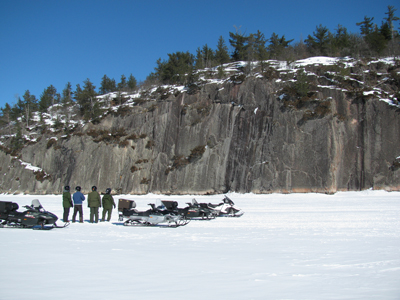 snowmobilers stopped and looking at cliffs