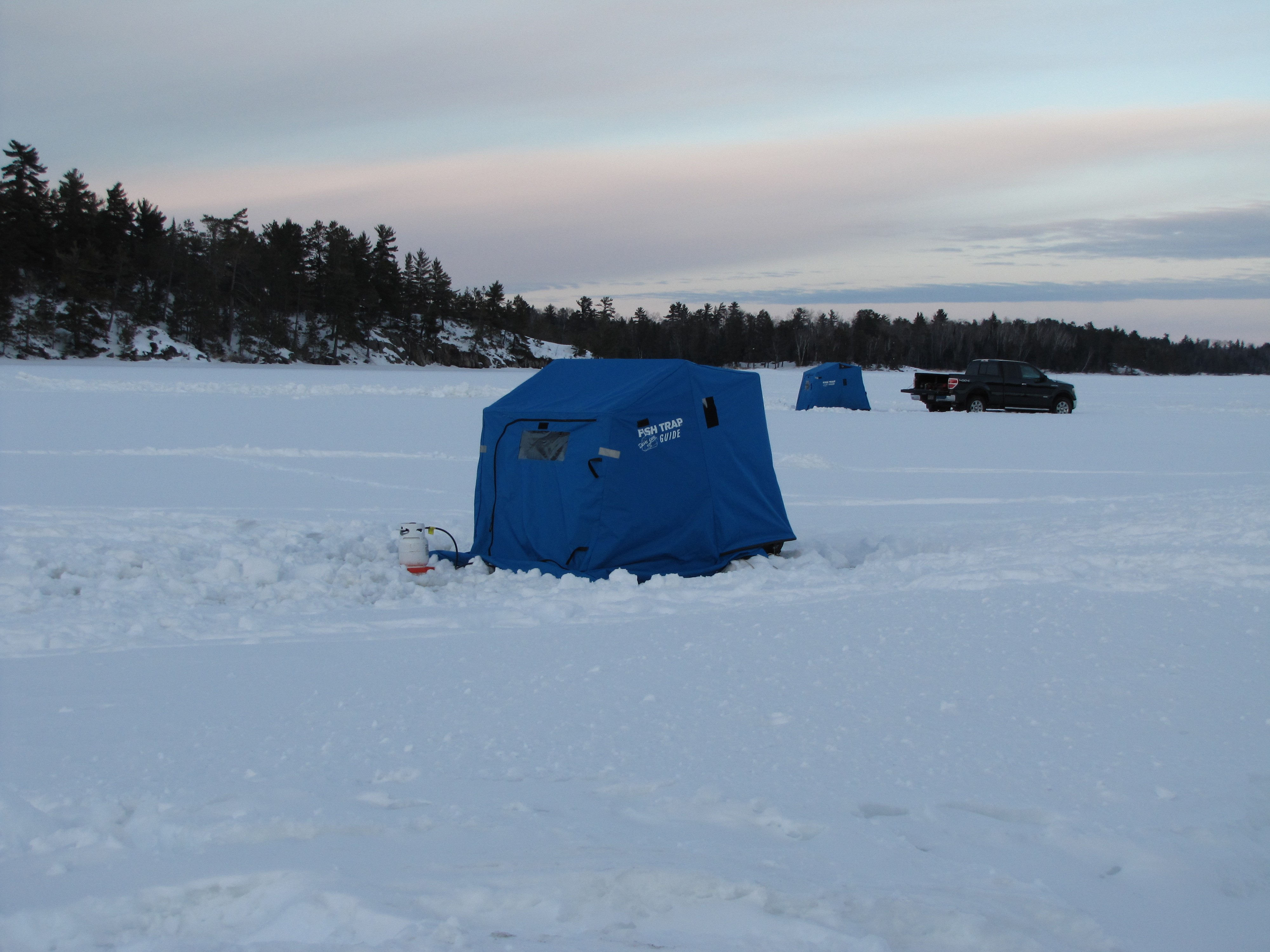 blue ice fishing shelter on frozen lake