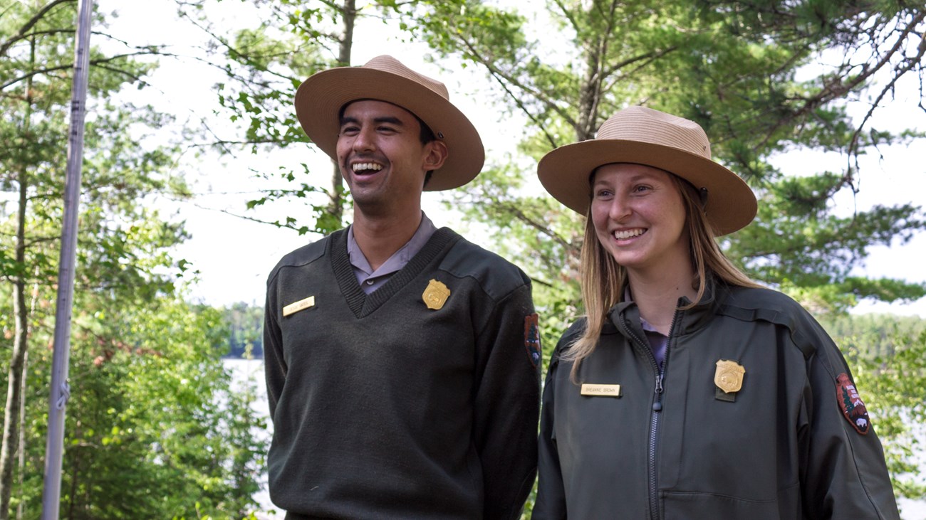 Two park rangers in uniform smiling