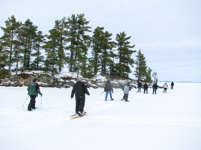 Visitors snowshoeing near an island on Rainy Lake