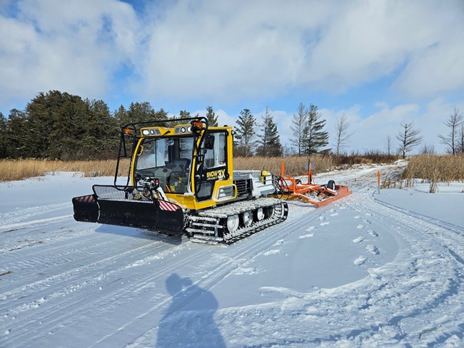 broomer on a portage trail under clear blue sky with fluffy white clouds.