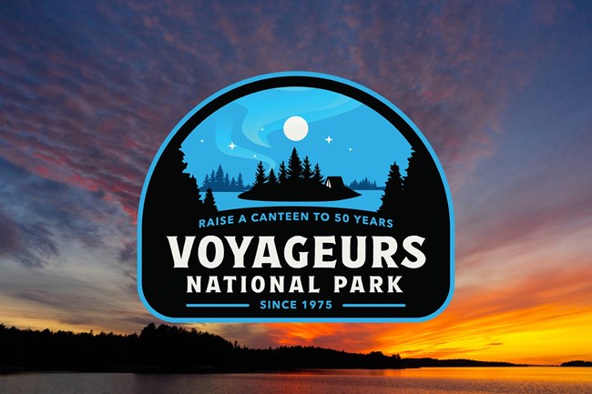 Oval 50th anniversary logo on top of a picture of a sunset over a lake.