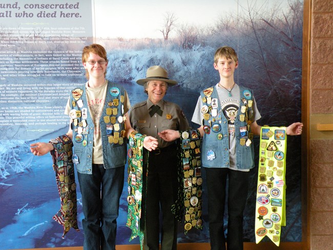 Two junior rangers showing off their junior ranger badges with a park ranger.