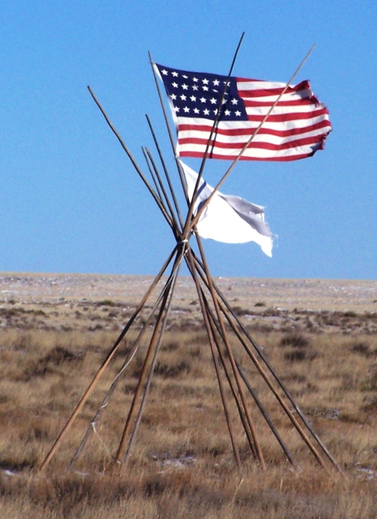 American flag and white peace flag on tipi poles