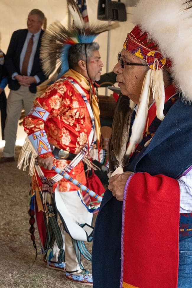 Cheyenne and Arapaho dancers in regalia dancing under a large tent.