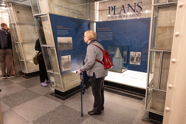 A visitor with a walking cane examines an exhibit in the Washington Monument