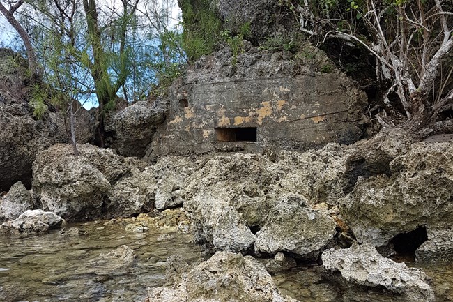 A concrete bunker build into a rock cliff with two openings.