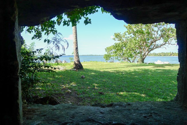 View of the ocean from a stone opening in a concrete bunker.
