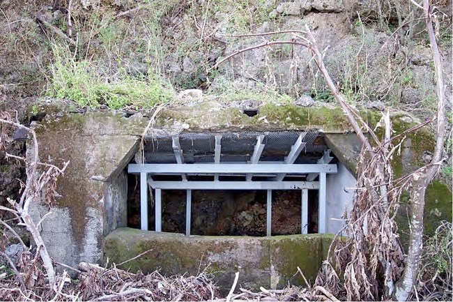 A concrete bunker built into the side of a cliff supported by a metal beams